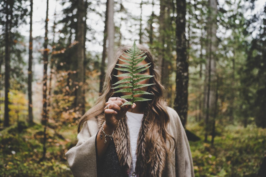 Woman Standing at Woods Holding Green Plant. Walk and Talk Therapy.